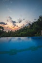 Infinity pool on tropical island with palm trees reflection. Sunset time Royalty Free Stock Photo