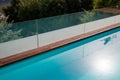 Infinity swimming pool with glassy safe fence and hardwood decking edge overlooking nature