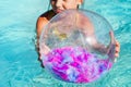 Inflatable beach ball transparent with pink feathers inside floating on the surface of the open sea pool Royalty Free Stock Photo