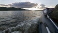 An inflatable boat with a motor rushes along the waves of the Volga river towards the sunset against