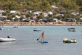 Inflatable boats moored in a calm bay and people paddling on stand up boards, on a campsite beach on Murter island, Croatia