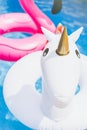 Inflatable colorful white unicorn and pink flamingo at the swim pool. Holidays time in the swimming pool with plastic