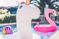 Inflatable colorful white unicorn and pink flamingo at the swim pool. Holidays time in the swimming pool with plastic