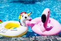 Inflatable colorful white unicorn and pink flamingo at the swim pool. Summer time in the swimming pool with plastic toys