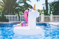 Inflatable colorful white unicorn and pink flamingo at the swimming pool. Fun time in the Summer at swimming pool