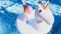 Inflatable colorful white unicorn at the swimming pool. Vacation time in the swim pool with plastic toys.Splash Water in Royalty Free Stock Photo