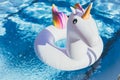 Inflatable colorful white unicorn at the swimming pool. Vacation time in the swim pool with plastic toys.Splash Water in Royalty Free Stock Photo