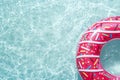 Inflatable float rubber ring in the form of a pink donut in the blue water of the pool