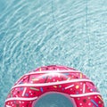 Inflatable float rubber ring in the form of a pink donut in the blue water of the pool