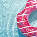 Inflatable float rubber ring in the form of a pink donut in the blue water of the pool