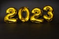Inflatable golden balloons numbers 2023 on a yellow background. Happy New Year. Flat lay. Copy space. Christmas. Happy