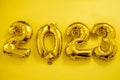 Inflatable golden balloons numbers 2023 on a yellow background. Happy New Year. Flat lay. Copy space. Christmas. Happy