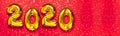 2020 inflatable golden numbers with confetti in the shape of stars on red background. New year winter decoration, holiday symbol.