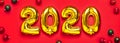 2020 inflatable golden numbers with red and green christmas balls on red background. New year winter decoration, holiday symbol,