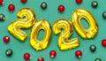 2020 inflatable golden numbers with red and green christmas balls on green background. New year winter decoration, holiday symbol