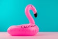 Inflatable mini flamingo on pastel blue and pink background. Pool float party, trendy summer concept. Flat lay, copy space.