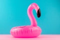 Inflatable mini flamingo on pastel blue and pink background. Pool float party, trendy summer concept. Flat lay, copy space.