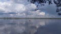 An inflatable motorboat floats on a lake. A colorful sky with clouds reflects in the water. A branch of a pine tree is leaning ove Royalty Free Stock Photo