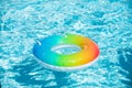 Inflatable ring floating in pool on summer background. Rainbow swimming pool ring float in blue water. Concept color Royalty Free Stock Photo