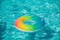 Inflatable ring floating in pool on summer background. Rainbow swimming pool ring float in blue water. Concept color Royalty Free Stock Photo