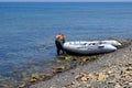 An inflatable rubber fishing boat on a rocky ocean shore is getting ready to go out to sea for fishing Royalty Free Stock Photo