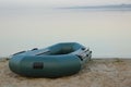 Inflatable rubber fishing boat on sandy beach near river Royalty Free Stock Photo