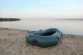 Inflatable rubber fishing boat on sandy beach near river Royalty Free Stock Photo