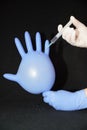 Inflated blue glove and gloved hand injecting a liquid with a syringe Royalty Free Stock Photo