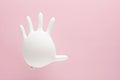 Inflated white medical glove with stop sign gesture on pink background