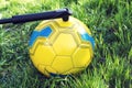 Inflating soccer ball with manual pump on green grass