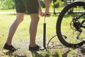 Inflating the tire of a bicycle. Cyclist repairs bike in forest. Bicyclist pumping air into the wheel. Biker uses a bicycle pump. Royalty Free Stock Photo