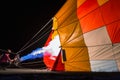 Inflating a very colorful balloon with the flame lit at night