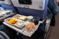 Inflight airplane Asian food set meal served consisting rice and spicy chicken, appetizer, dessert, bun and red wine Royalty Free Stock Photo