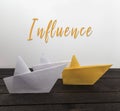 Influence, leadership concept. Paper boats on wood with inscription: Influence. Royalty Free Stock Photo