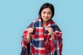 Influenza Concept. Chinese woman in plaid blanket standing on grey holding cough syrup smiling positive
