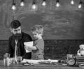 Informal education concept. Art lesson in the kindergarten. Cute boy showing teacher his drawing