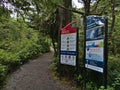 Information board with warning at trailhead of Wild Pacific Trail in Ucluelet, Vancouver Island surrounded by rainforest. Royalty Free Stock Photo