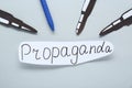 Information warfare concept, journalism and media influence. Pen and paper bullets aimed at card with word Propaganda on white Royalty Free Stock Photo