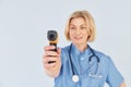 With infrared thermometer. Middle-aged professional female doctor in uniform and with stethoscope