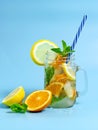 Infused detox water with ice, lemon and oranges slices with mint on blue background. Iced cold summer cocktail or lemonade in Royalty Free Stock Photo