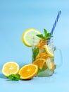 Infused detox water with ice, lemon and oranges slices with mint on blue background. Iced cold summer cocktail or lemonade in Royalty Free Stock Photo