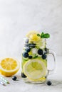 Infused detox water with lemon and cucumber slices, blueberry and mint. Ice cold summer lemonade in glass mason jar