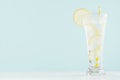 Infused fitness mineral tonic water with yellow lemon slices, ice cubes, yellow straw in elegant glass on white wood table, mint. Royalty Free Stock Photo