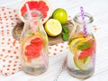 Infused flavored water with fresh fruits on white wooden background.