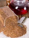Infuser with dry rooibos leaves on grey wooden table, closeup