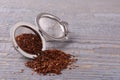 Infuser with dry rooibos leaves on grey wooden table, space for text