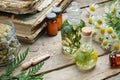 Infusion bottles, Chamomile flowers and Thuja plant, bottles of homeopathic globules and old books