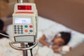 Infusion pump feeding IV drip into child patient while she is sleeping on bed in hospital Royalty Free Stock Photo