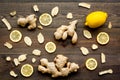 Ingredient for warming tea. Whole and sliced ginger roots, lemon on dark wooden background top view