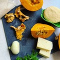 Ingredients for autumn risotto, pumpkin, chanterelle mushrooms, butter, onion, parsley, cheese, vegetables on a board